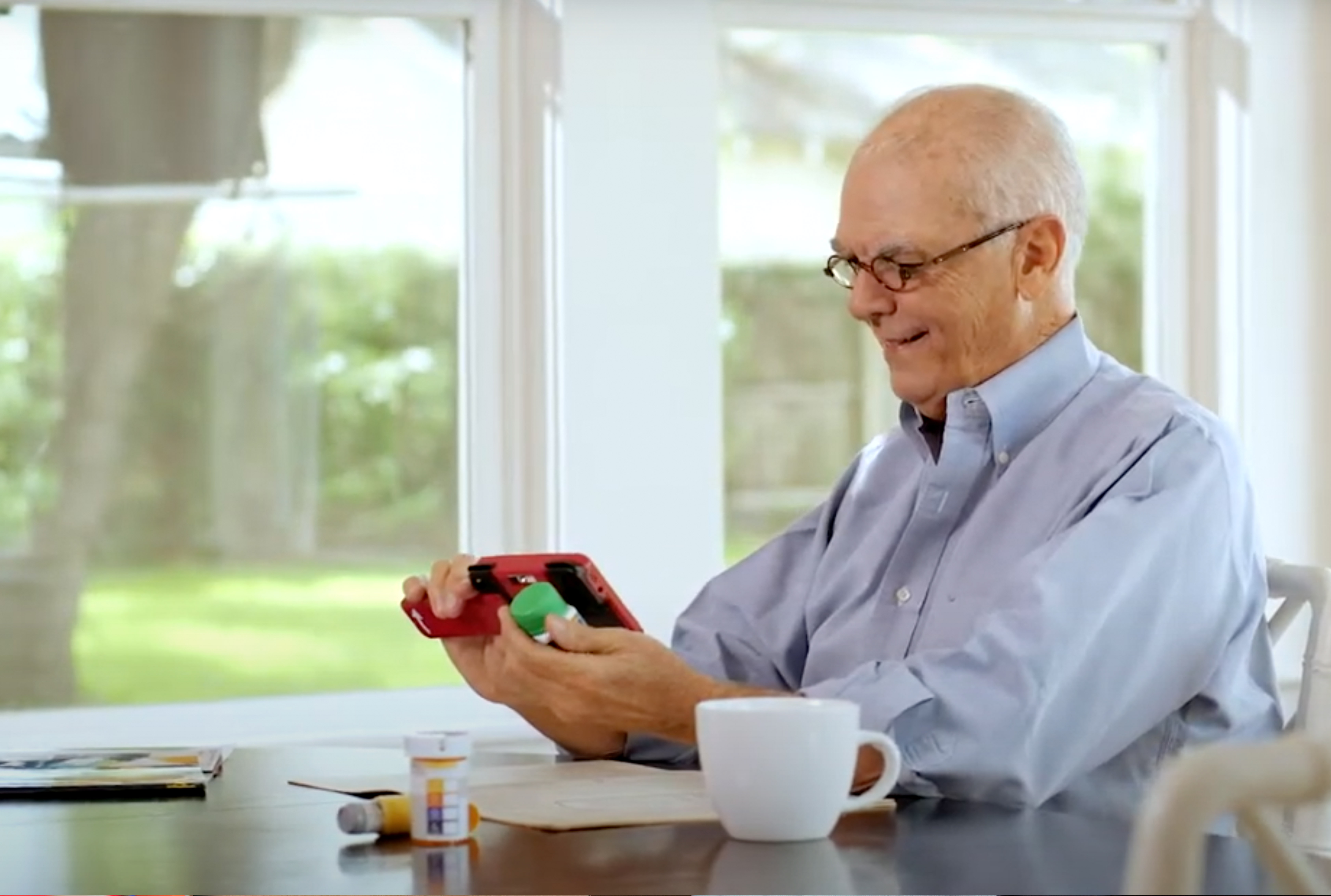 Man using the Ruby 7-inch handheld video magnifier to read a newspaper at home